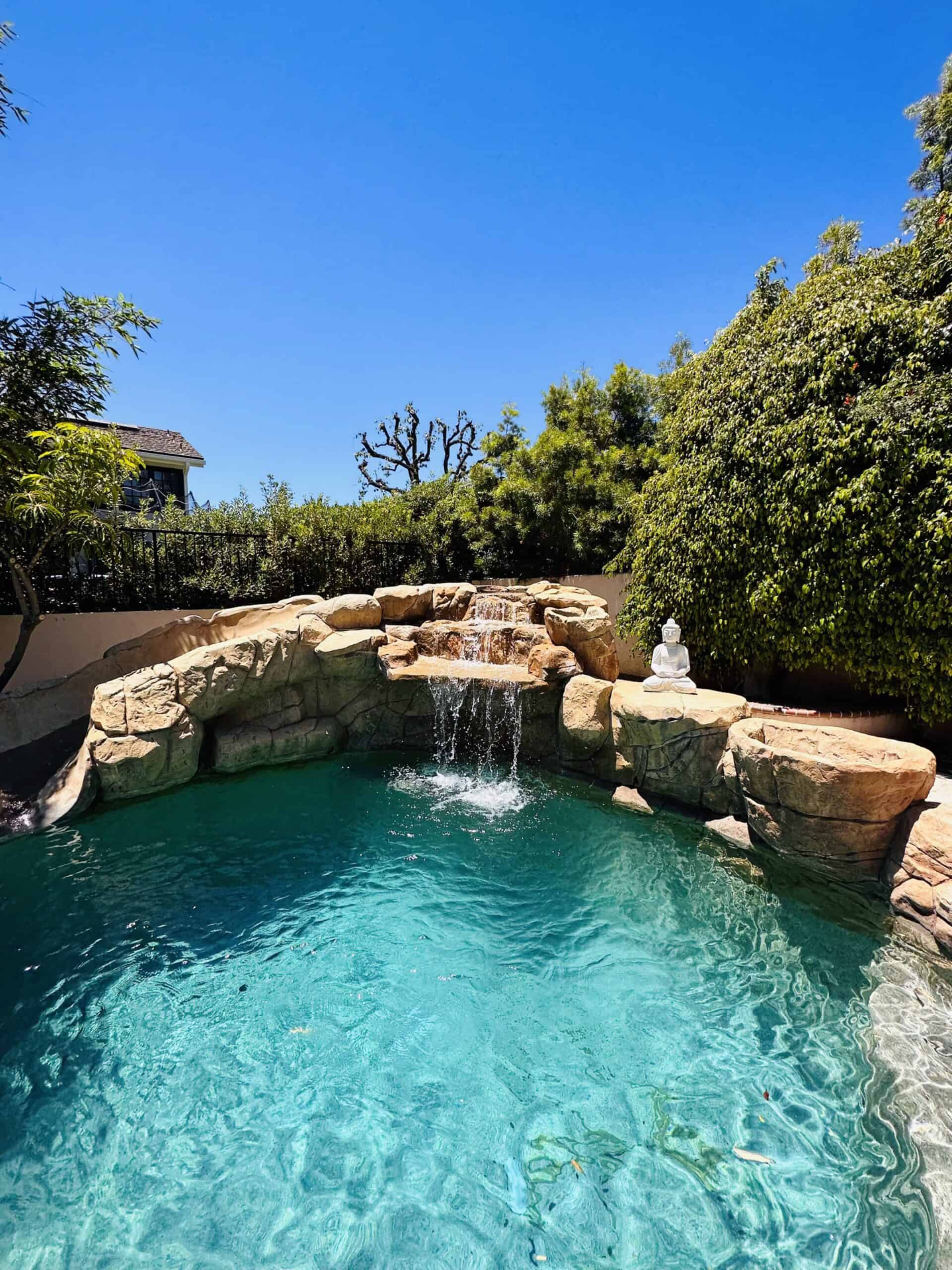 Outdoor pool with rock waterfall and garden